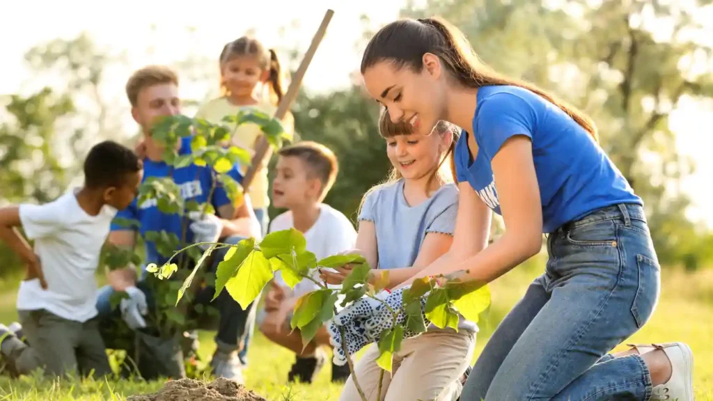 group of people and small kids planting saplings