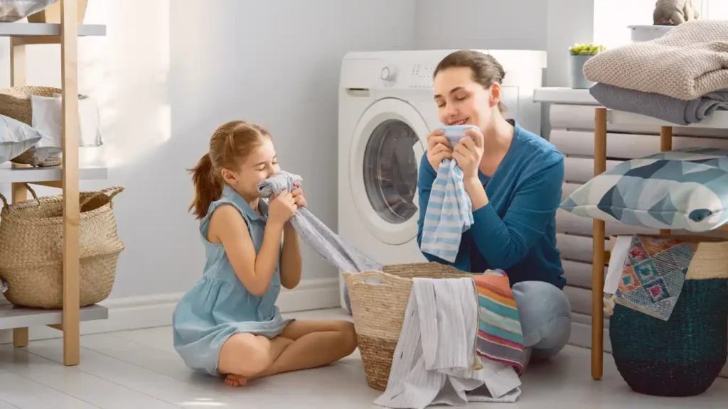 A mother and a child sitting next to the washing machine and smelling fresh clothes washed in toxic free detergent