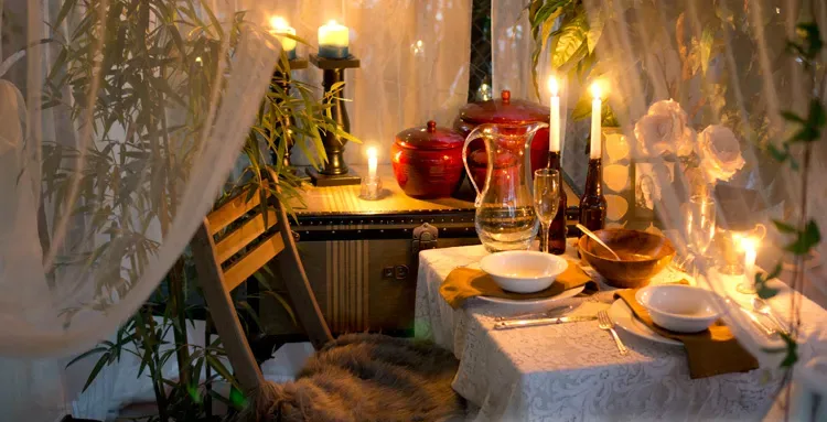 A beautiful dinner table with candles and clay utensils.